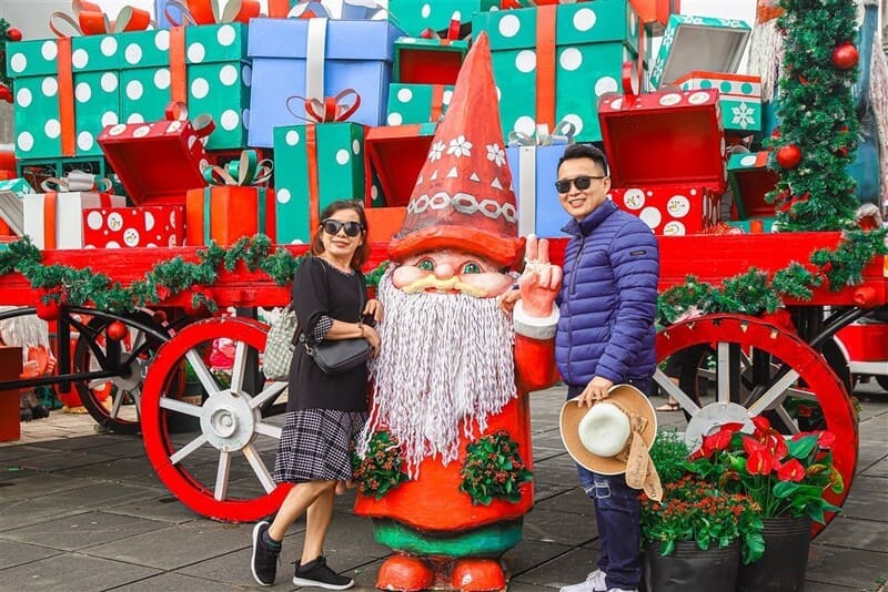 Du khách tạo dáng bên cỗ xe quà tặng và người tuyết tại quảng trường Noel